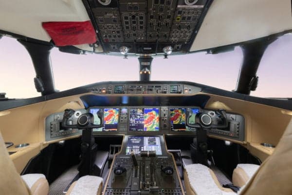 The cockpit of a Global Express aircraft with multiple display screens and tan leather.