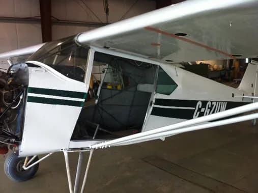 The side of a white and green aircraft, C-GZUW, is open for maintenance.