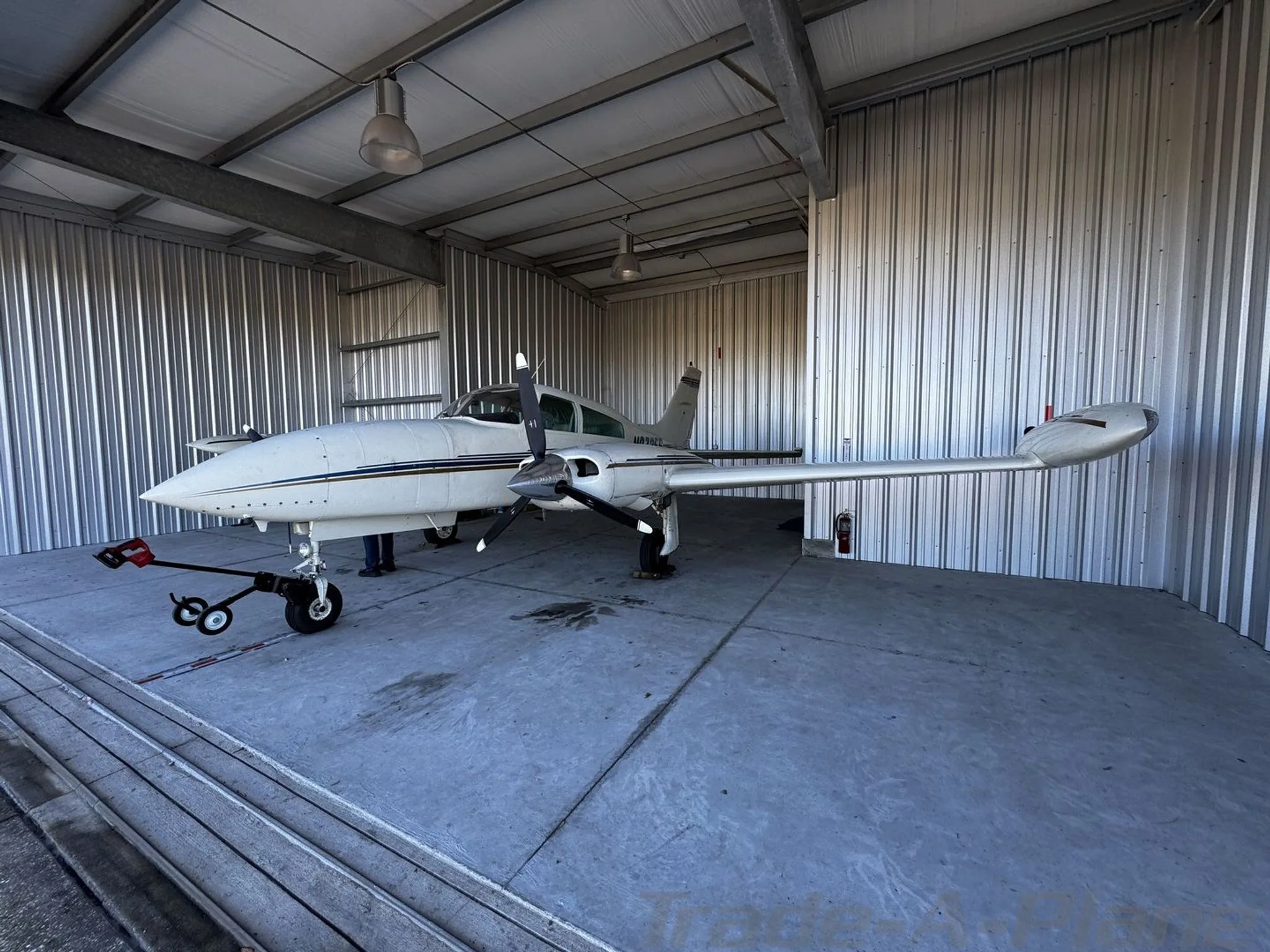 A white twin-engine aircraft, registration N87356, parked inside a metal hangar.