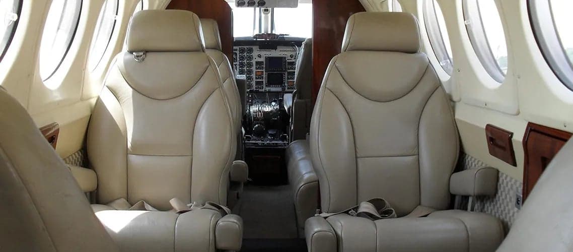 Forward view of the aircraft's interior with leather seats and cockpit in the background.