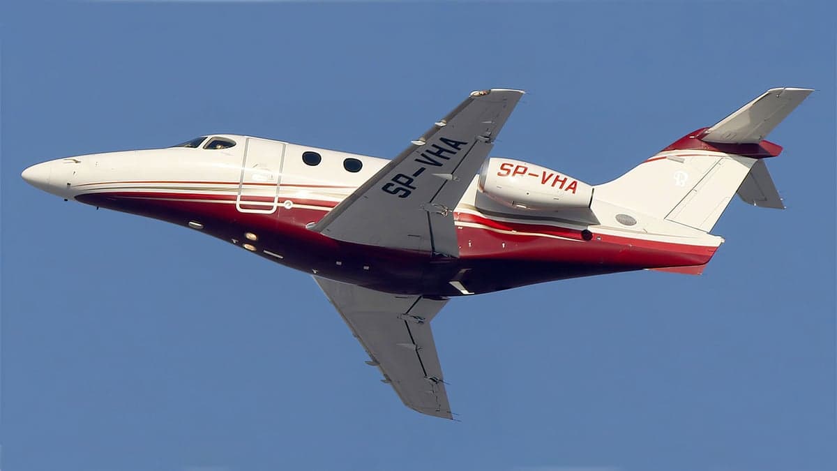SP-VHA aircraft in flight with a red and white paint scheme.