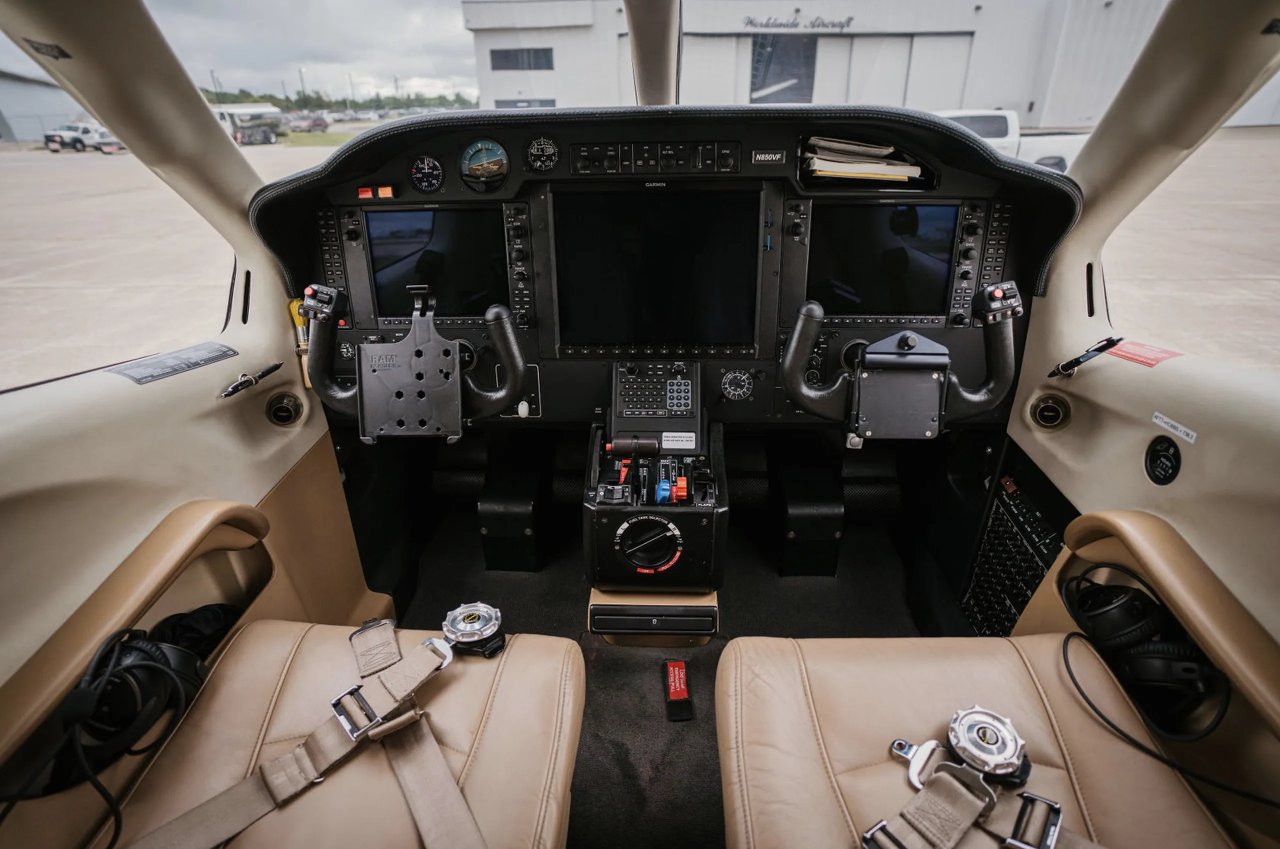 View of the aircraft cockpit with dual screens and tan leather seats.