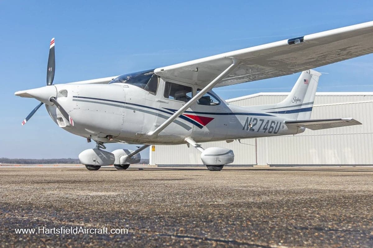 A Cessna Skylane aircraft with a white and gray paint scheme parked on the tarmac.