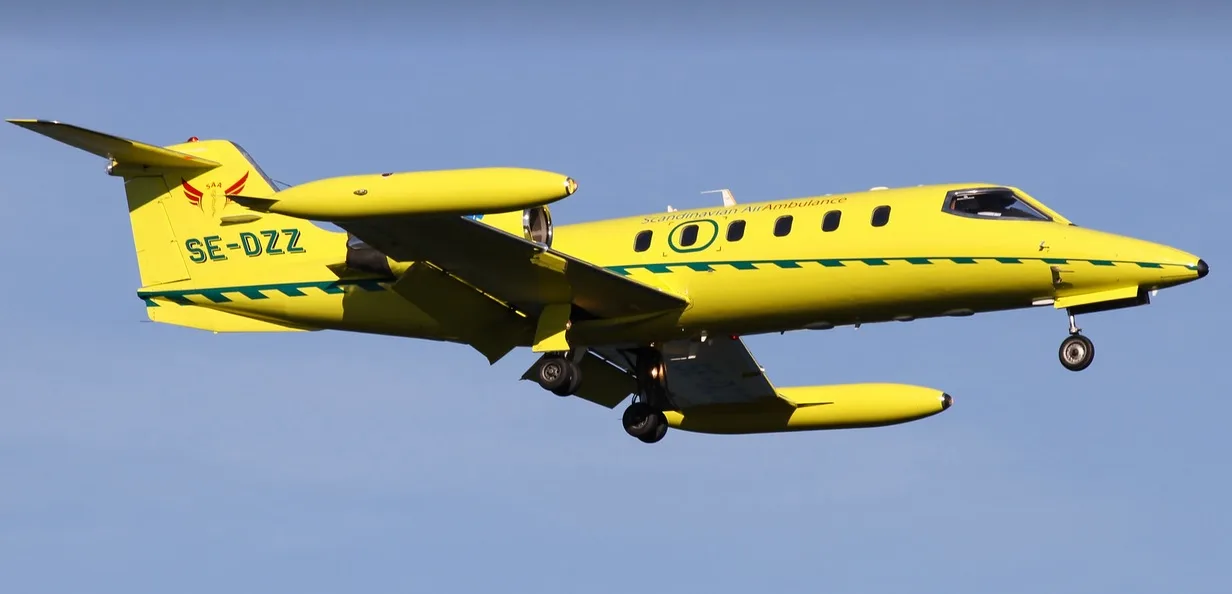 Yellow Scandinavian Air Ambulance jet in flight.