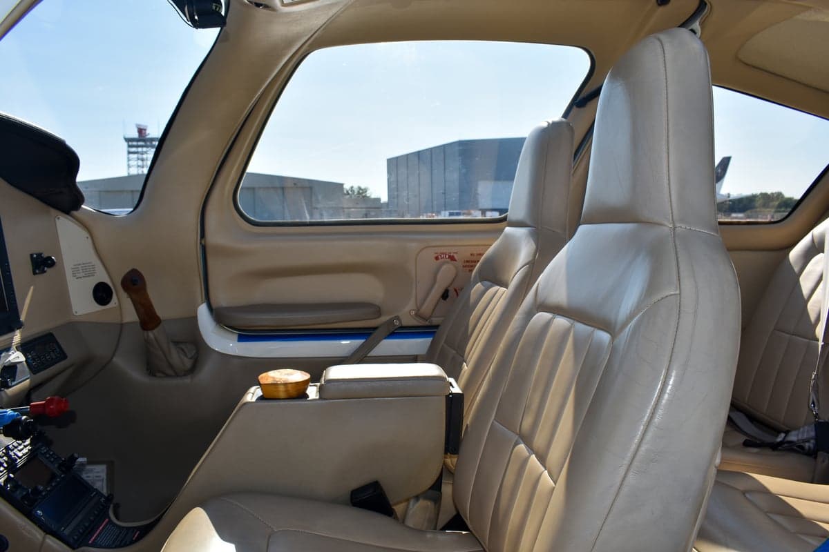 View of the aircraft's interior with tan leather seats and seatbelts.