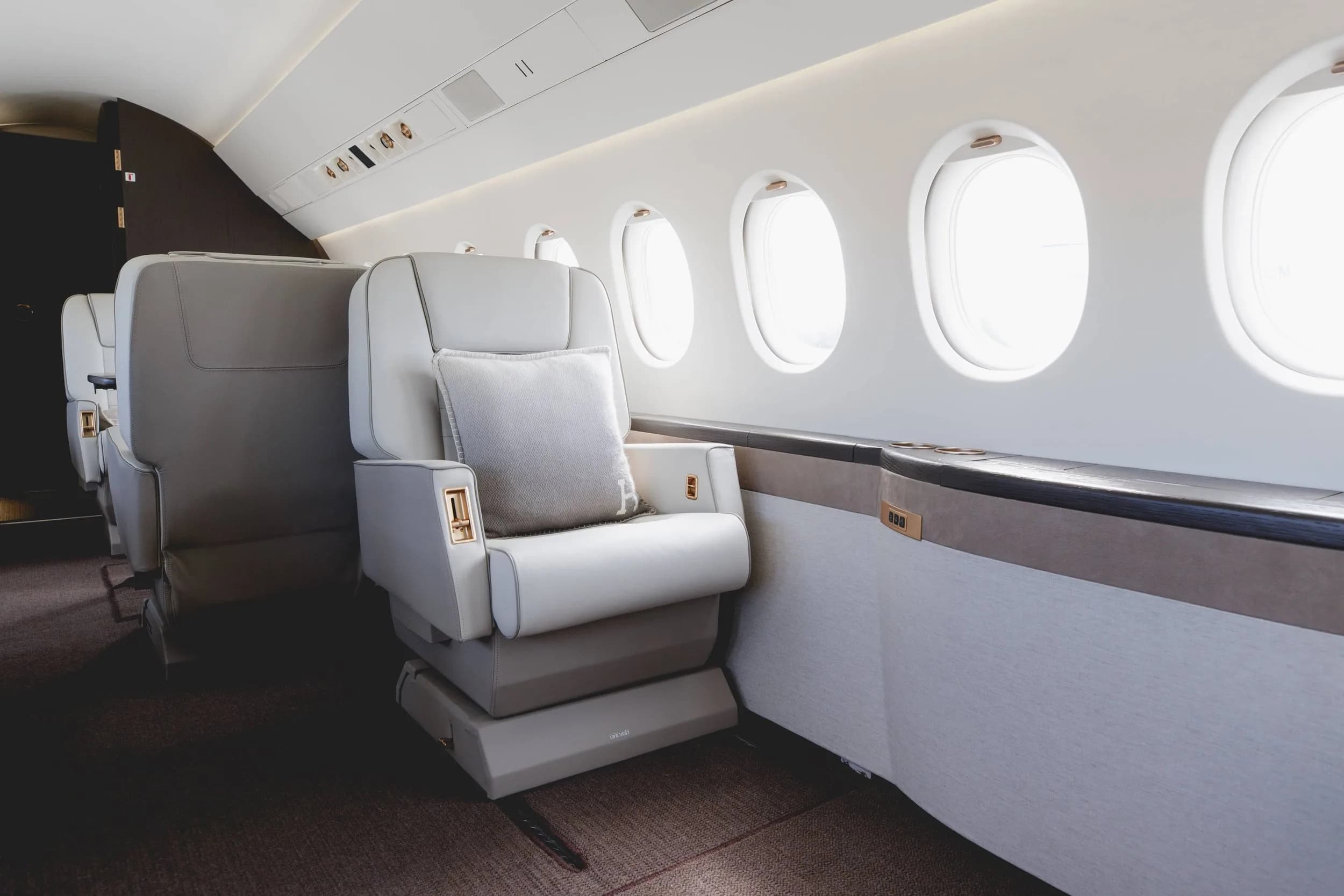 A view of the luxurious white leather seats and windows inside the aircraft cabin.