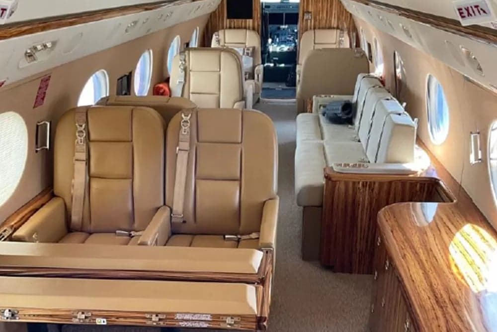 View of the aircraft's cabin with tan leather seats and wood accents.