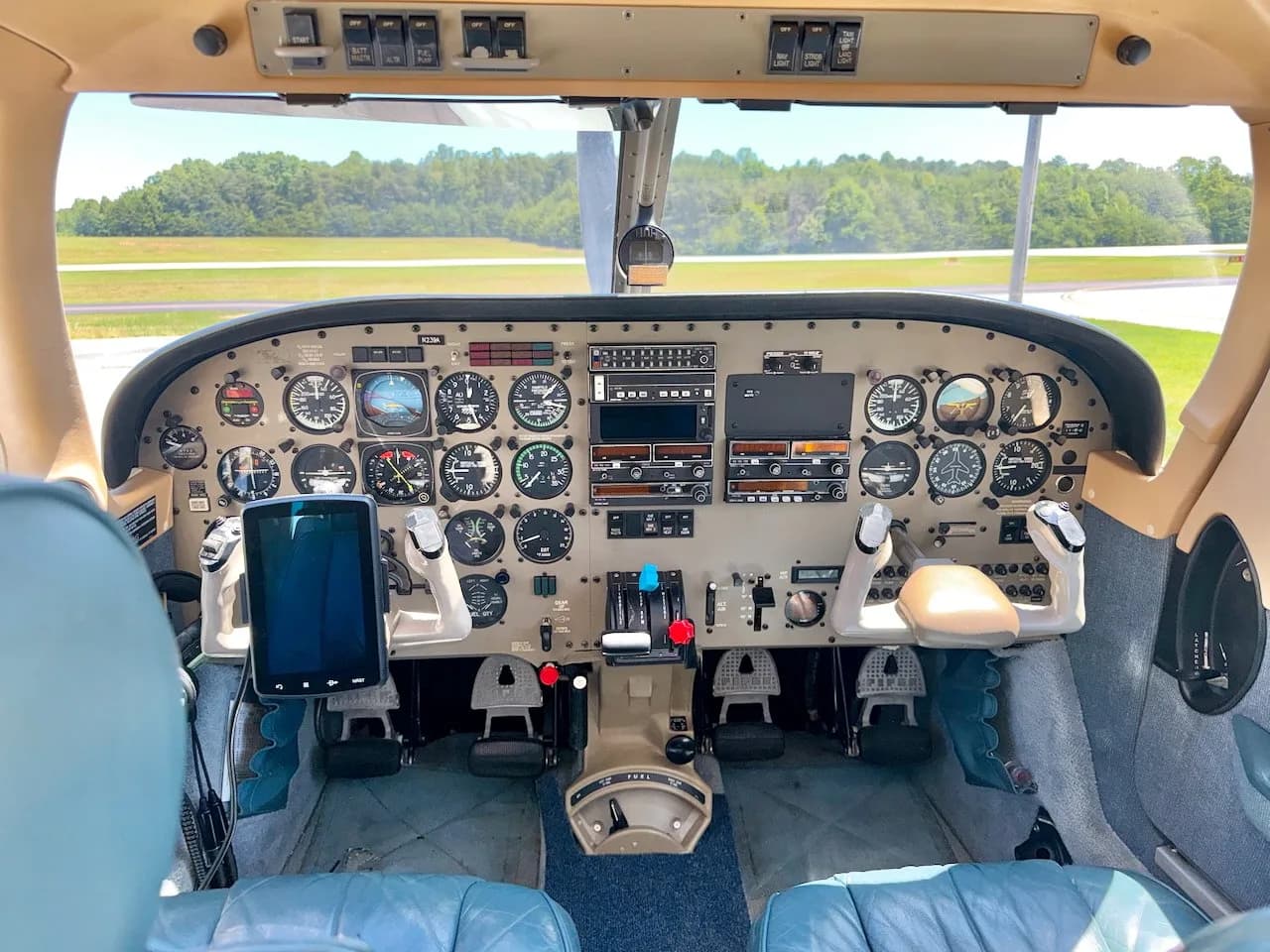 The cockpit of a small aircraft, showing the instrument panel, yokes, and throttle quadrant with blue leather seats.