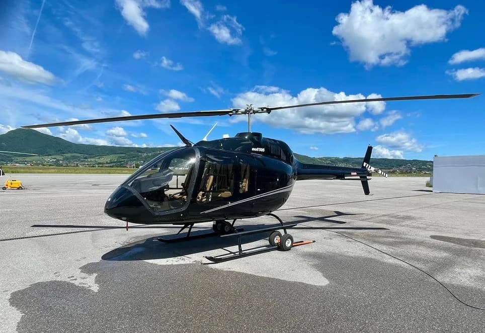 Bell 505 helicopter parked on the tarmac with a black paint scheme.