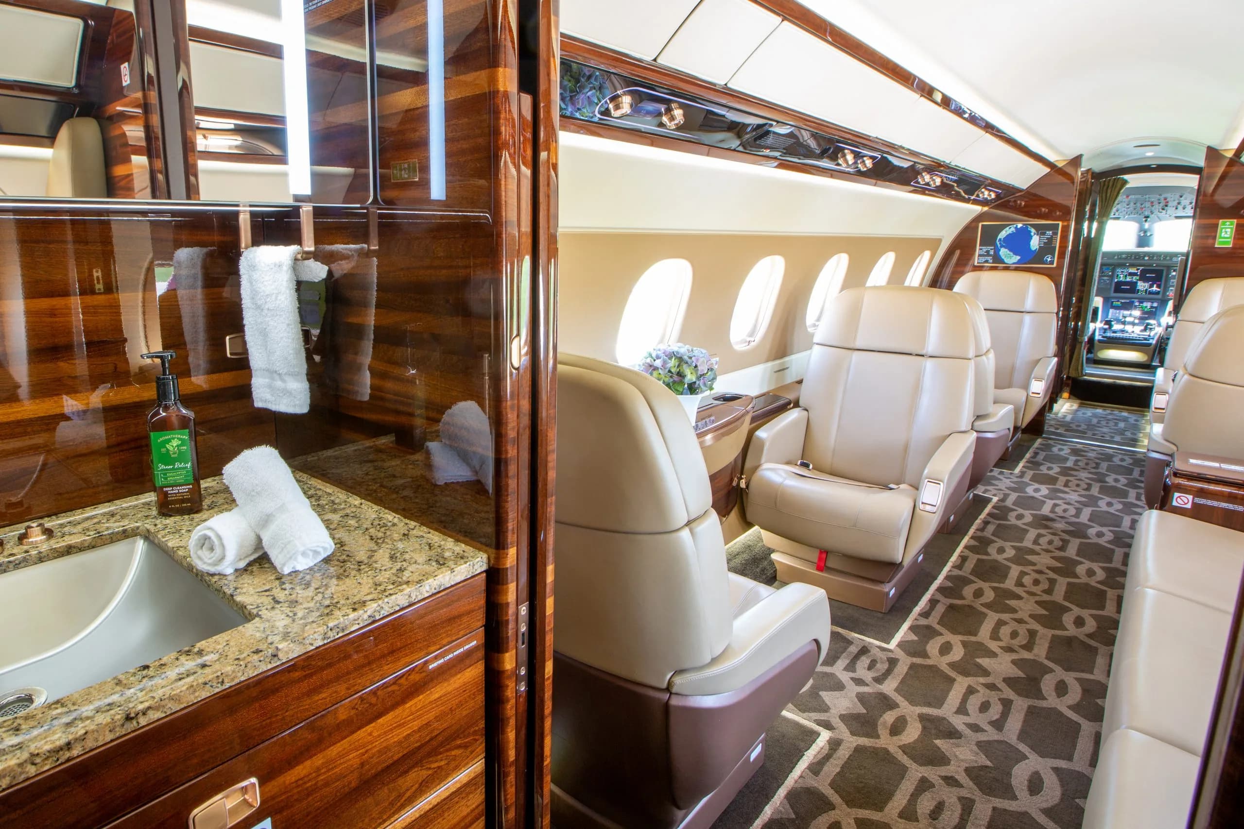 The interior of an Embraer Phenom 300E with a view of the lavatory and cabin seats.