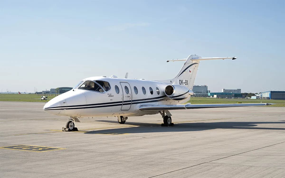 A white Beechjet 400A with black stripes is parked on an airport tarmac under a clear blue sky.