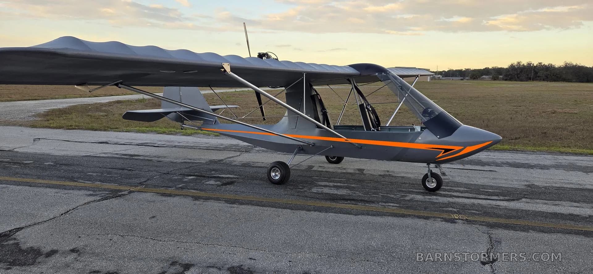A gray aircraft with orange accents on the runway.