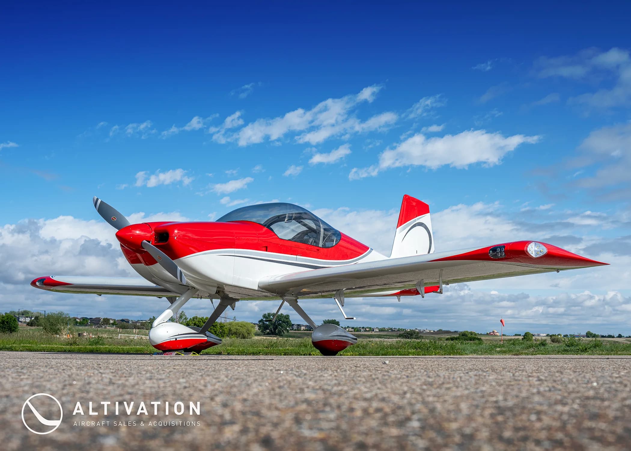 A red and white experimental aircraft with registration N918ZH parked on an asphalt runway under a blue sky with scattered clouds.