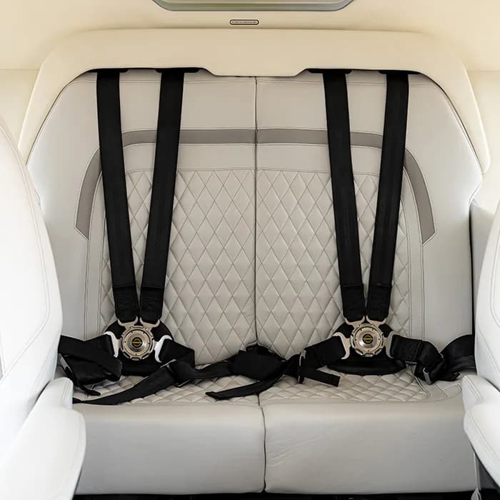 Close-up of the white leather seats with black seatbelts in the helicopter's interior.