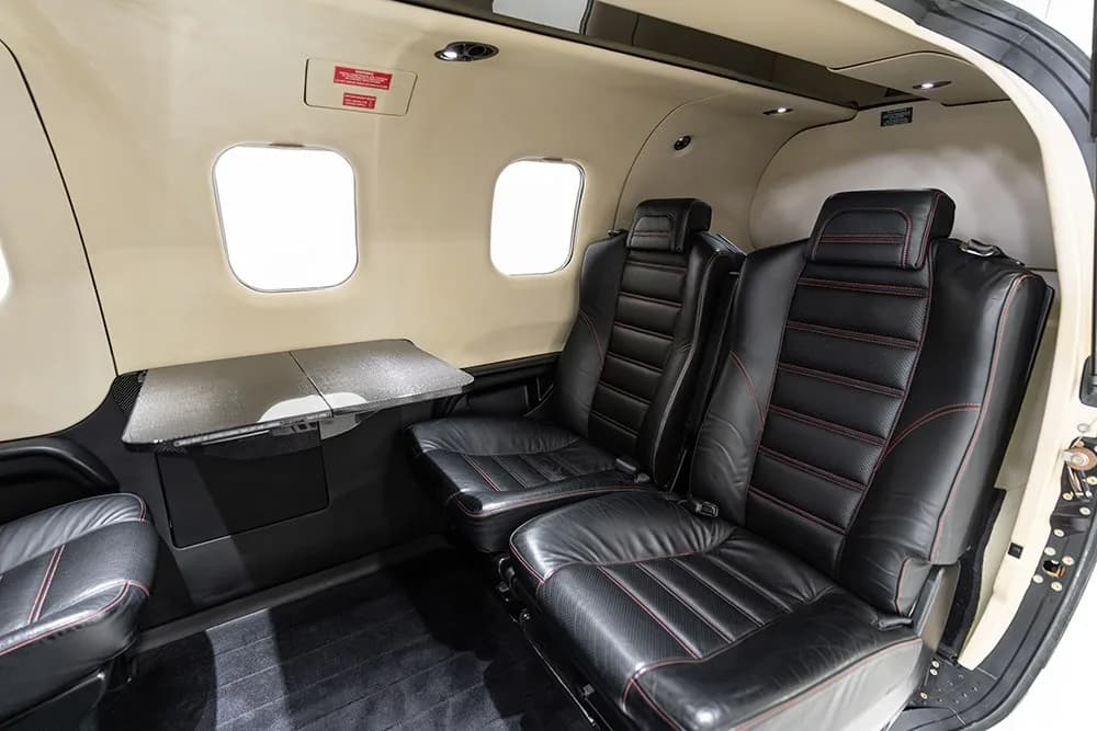 The TBM 930 cabin interior with two black leather seats and a fold-out table.