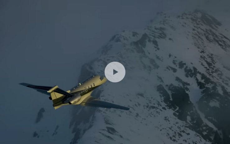A Pilatus PC-24 flying near a snowy mountain range.