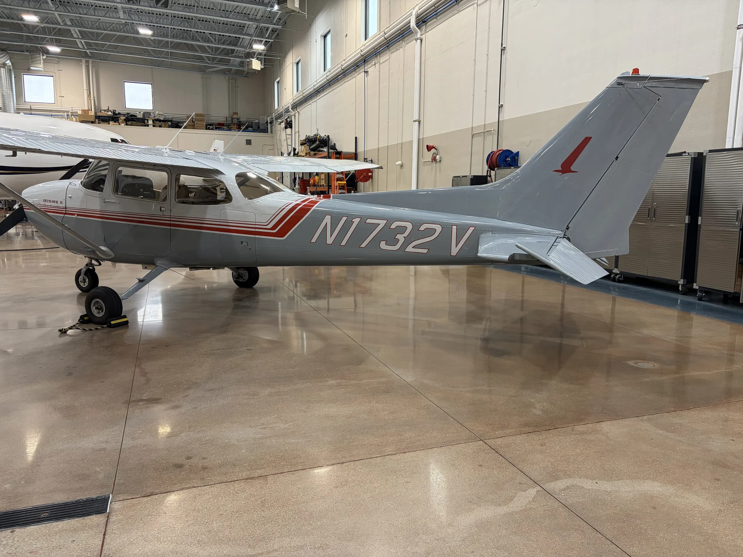 Cessna 172 with gray and red paint scheme in a hangar.