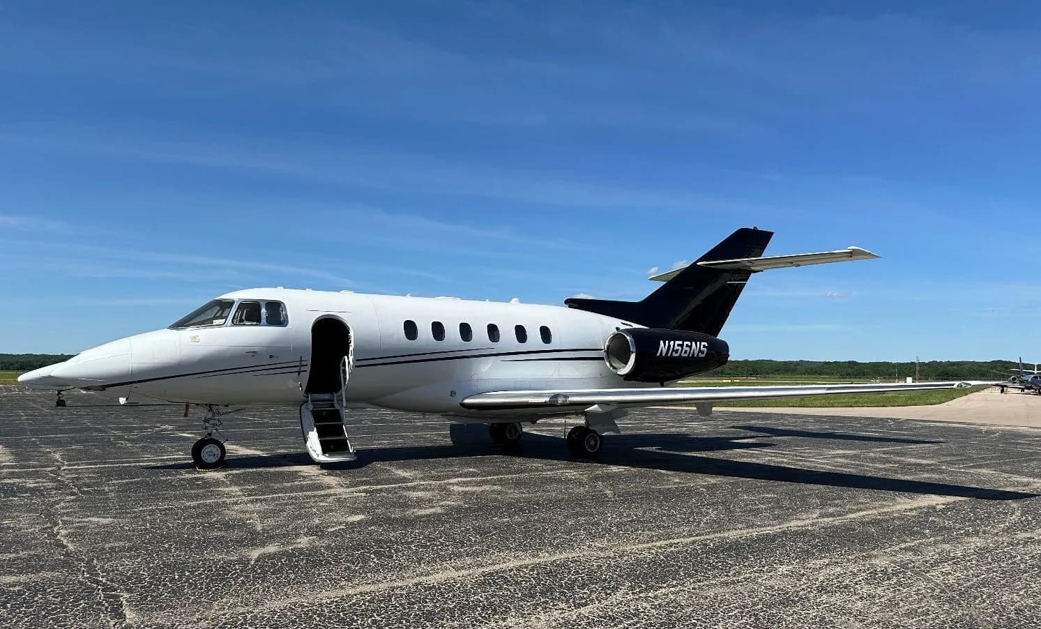 Hawker 400XP, registration N156NS, parked on the tarmac with the airstair door open.