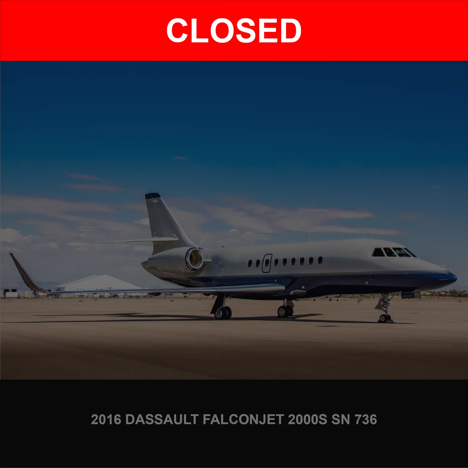 A 2016 Dassault Falconjet 2000S, painted white and blue, parked on an airport tarmac under a clear sky.