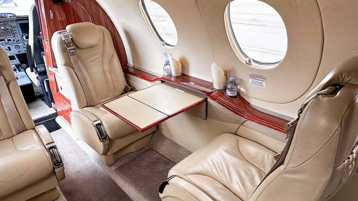 Aircraft interior with leather seats and a small table.