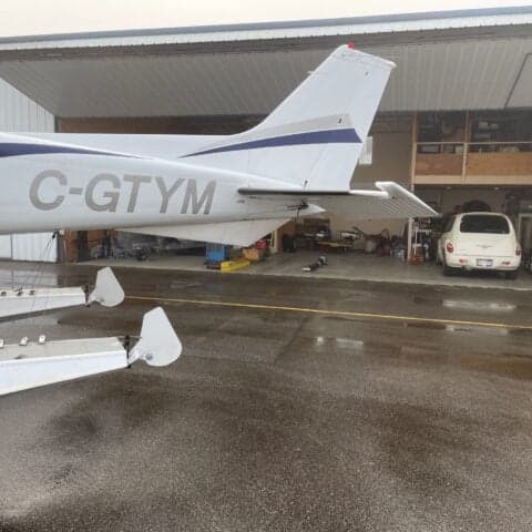 Tail section of C-GTYM Cessna floatplane, parked outside a hangar.