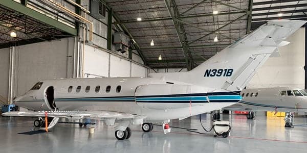 A white and blue Falcon jet is parked inside a hangar.