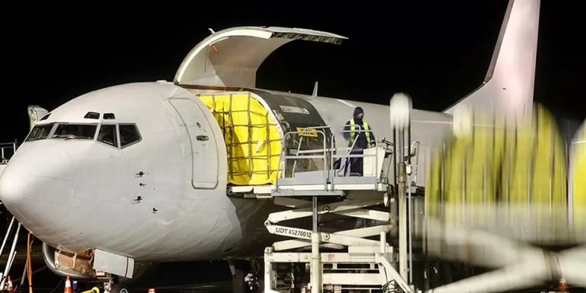 A cargo plane is being loaded with cargo at night.