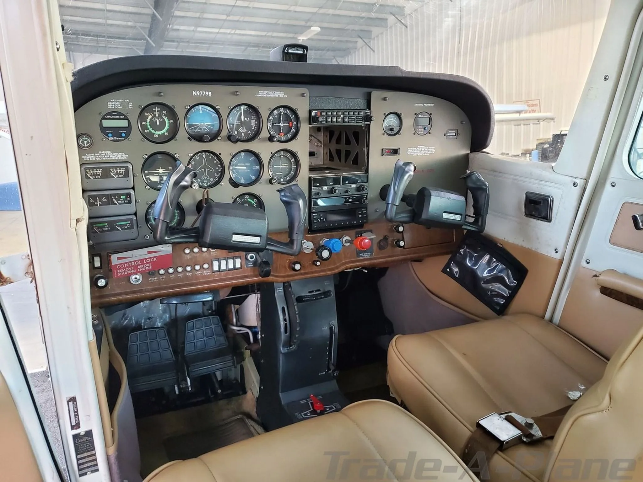 The cockpit of a Cessna Cutlass RG II (N9779B) showing the instrument panel, yokes, and tan seats.