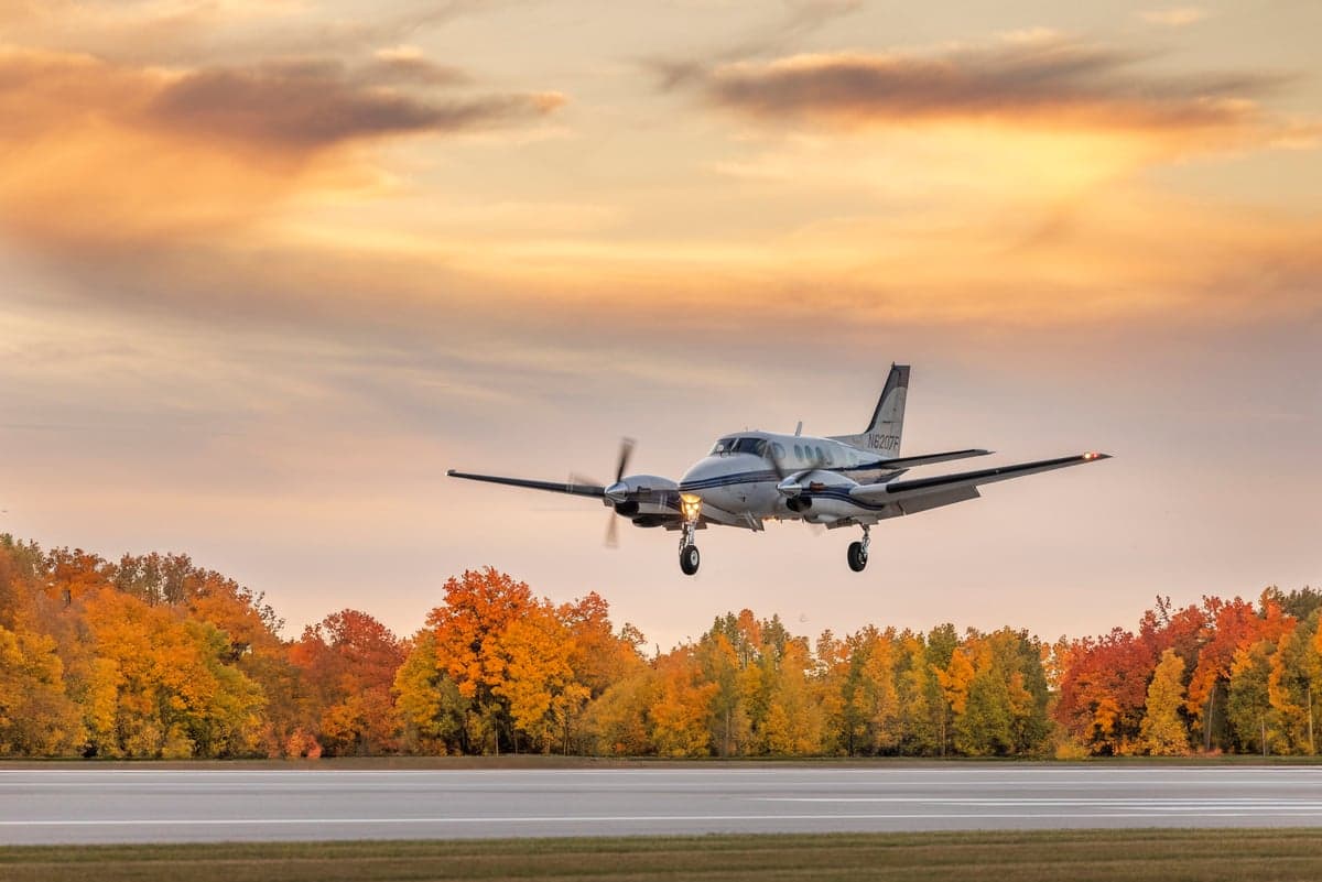 A twin turboprop aircraft on final approach at sunset.