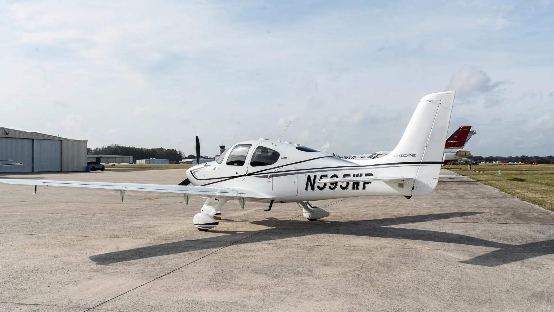 Rear 3/4 view of a white Cirrus SR22 aircraft with N595WP registration on an airfield.