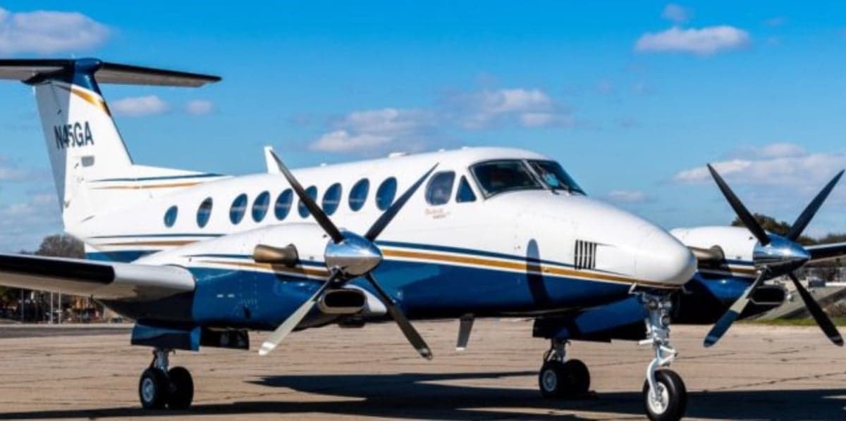 A white and blue twin-turboprop aircraft, tail number N45GA, is parked on an tarmac under a clear blue sky.
