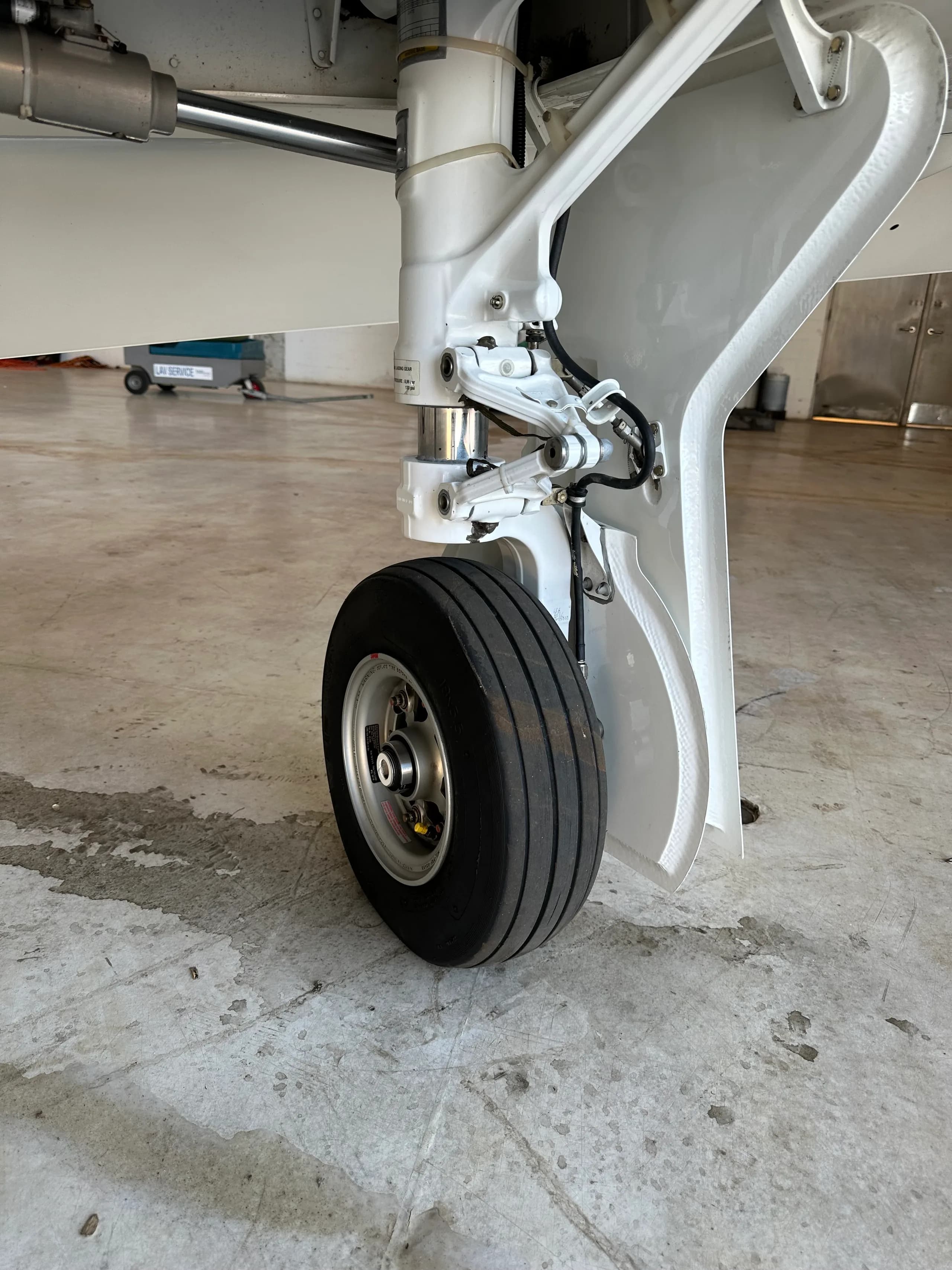 A close-up view of the nose landing gear of an aircraft in a hangar.