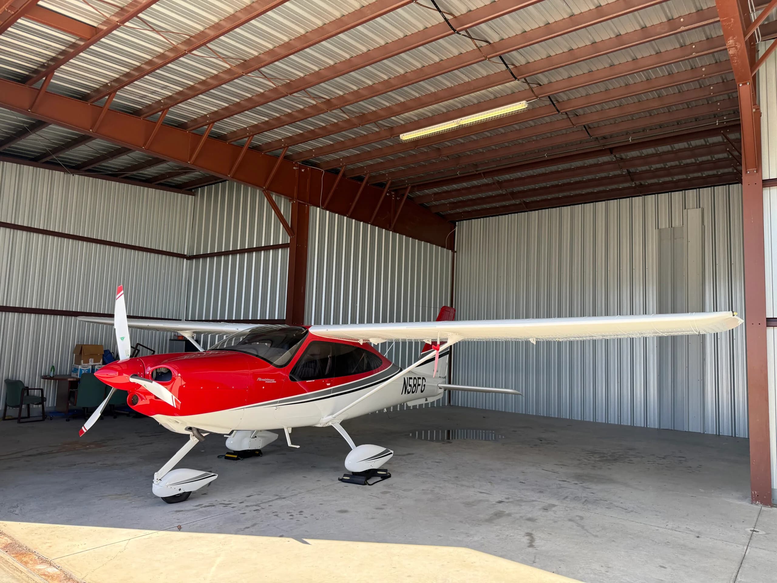 Tecnam P2010 aircraft N58FG parked in a hangar with a red and white paint scheme.