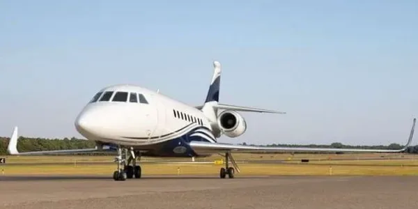 A white and blue Pilatus PC-12 turboprop aircraft, N80B, is parked on the tarmac in front of a hangar.