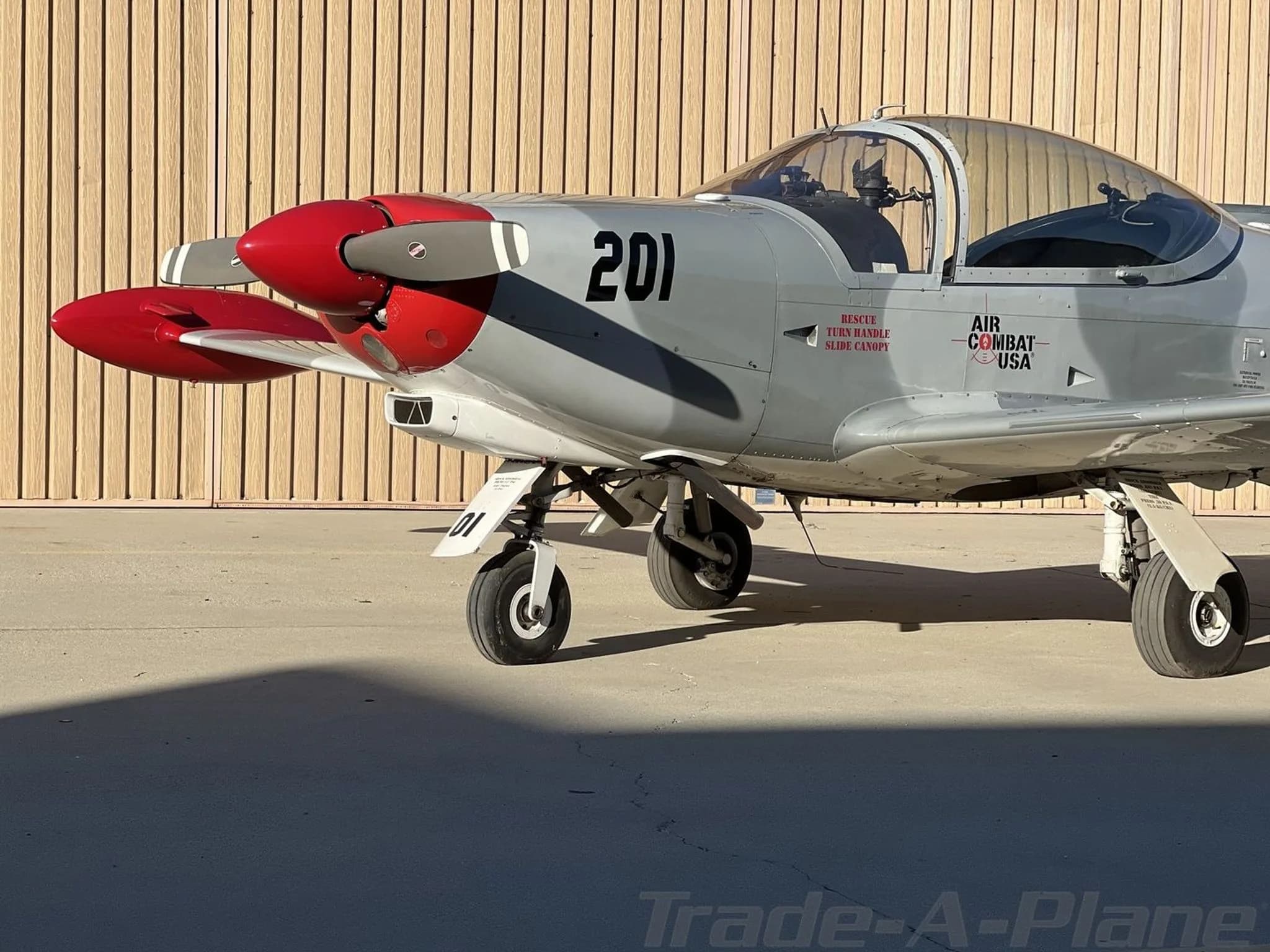 A front-left view of the grey and red Air Combat USA aircraft '201' parked on the tarmac.