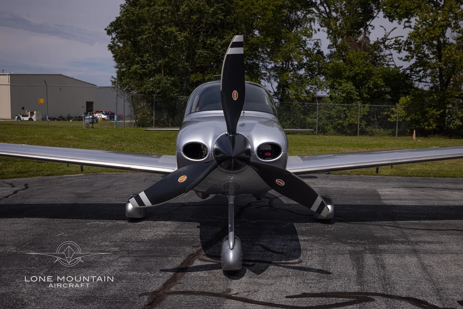 A head-on view of a silver and red Cirrus SR22T aircraft with registration N211CK parked on an asphalt ramp.