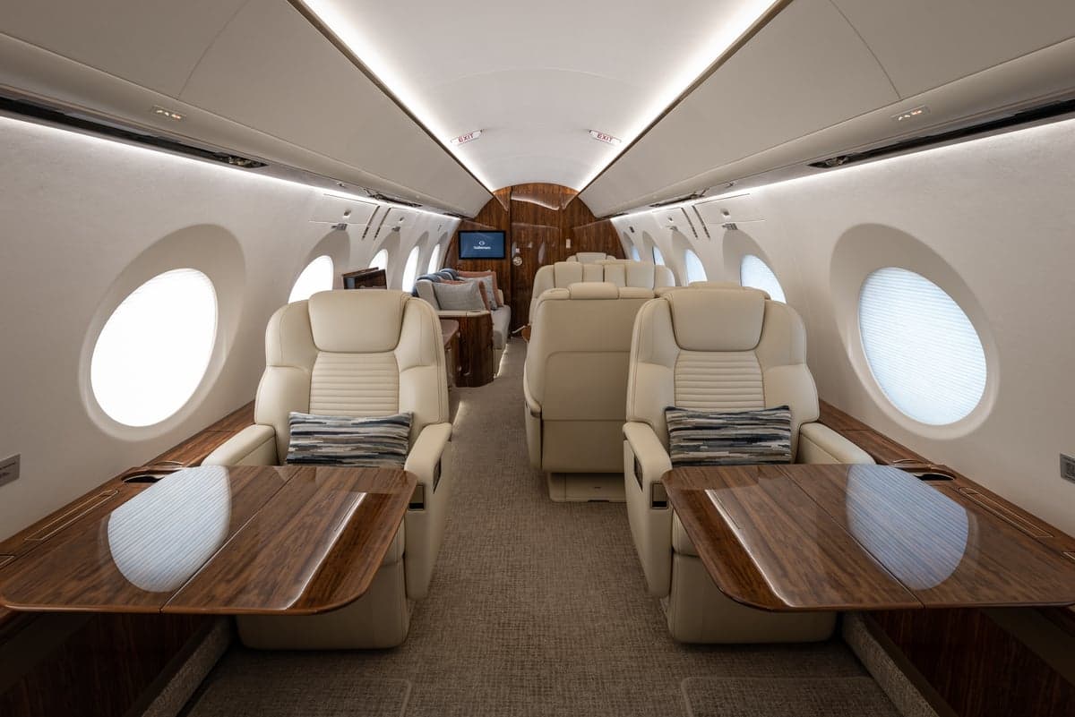 The interior of the aircraft features comfortable seating and wood accents.