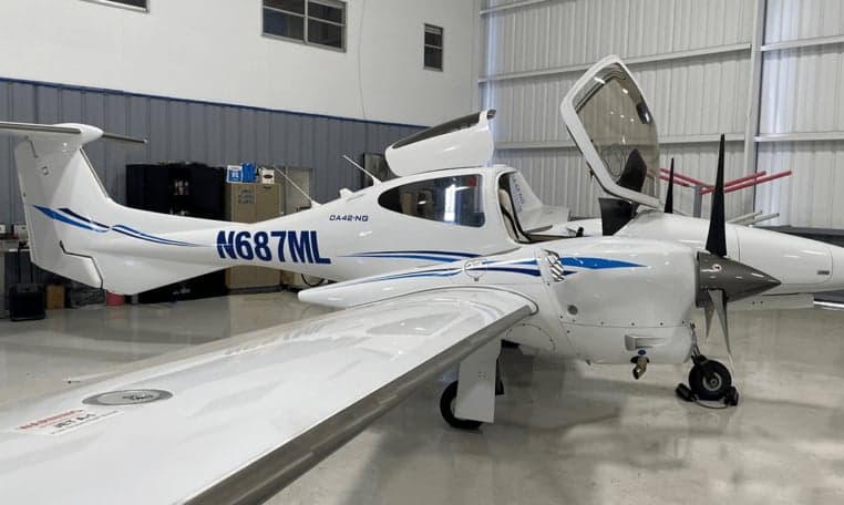 Diamond DA42-NG aircraft N687ML with open doors inside a hangar.