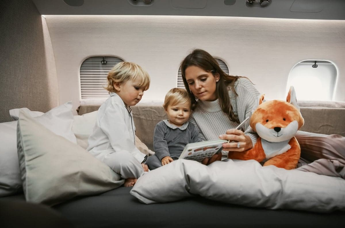Interior of the aircraft with a woman and two children reading a book.