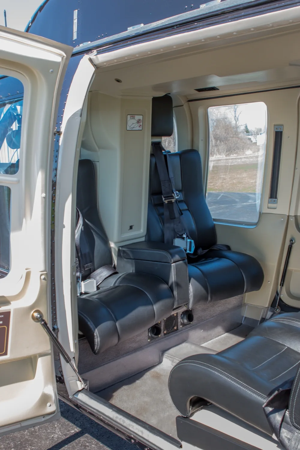 The black leather passenger seats in the rear cabin of the helicopter, viewed through an open door.