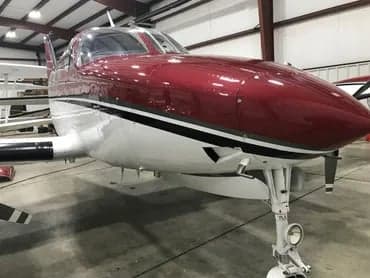 The front of the maroon and white Cessna 340A aircraft is shown with the landing gear extended.