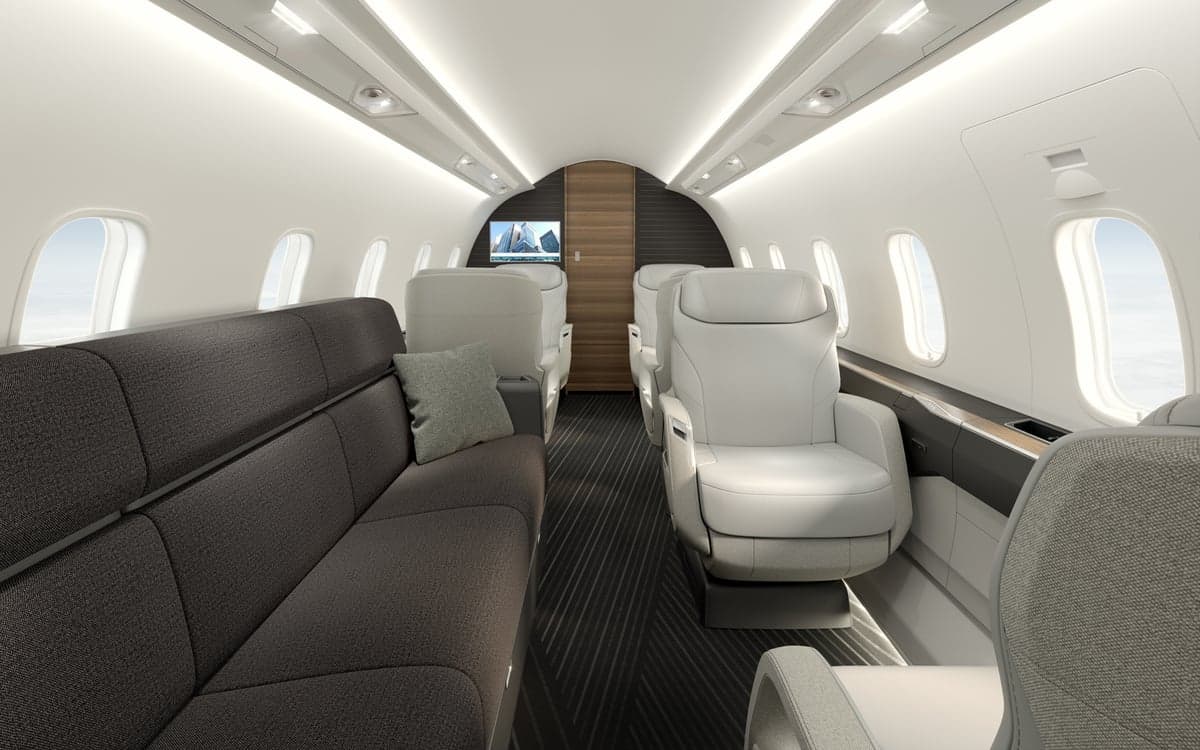 A view of the Challenger 3500 cabin with a sofa and white leather seats.