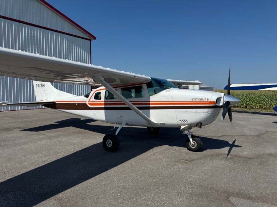 A Cessna Stationair 6 on the tarmac in front of a hangar.