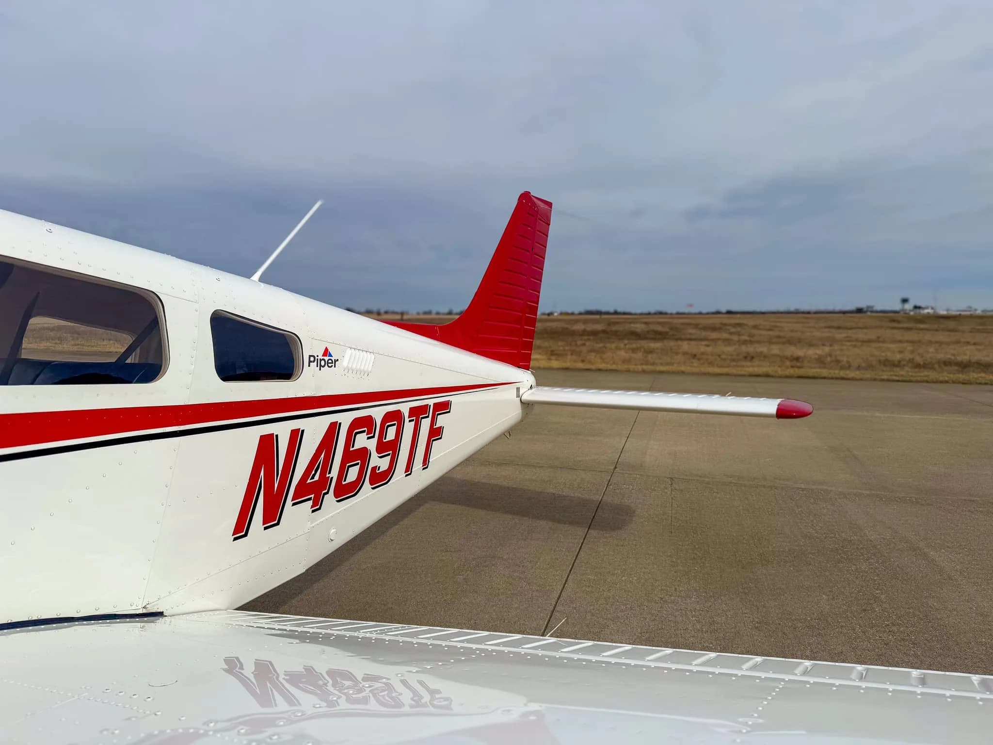 A close-up of the tail section of a white and red Piper Archer TX aircraft, N469TF.