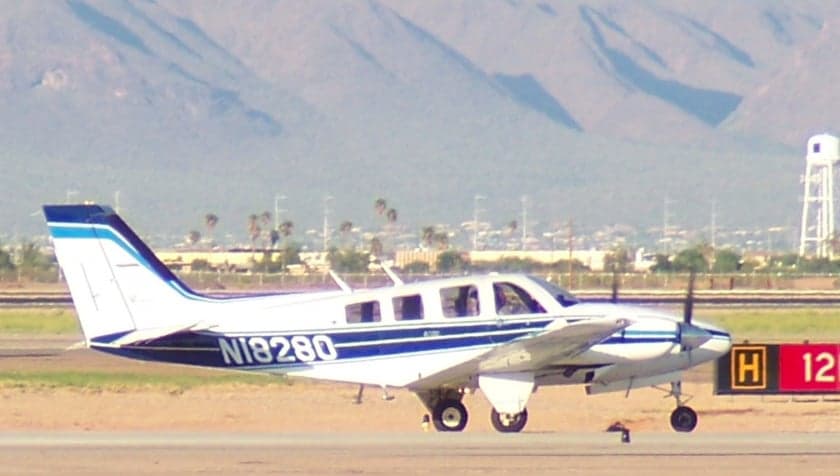 Beechcraft Baron N18280 taxiing on the runway with mountains in the background.