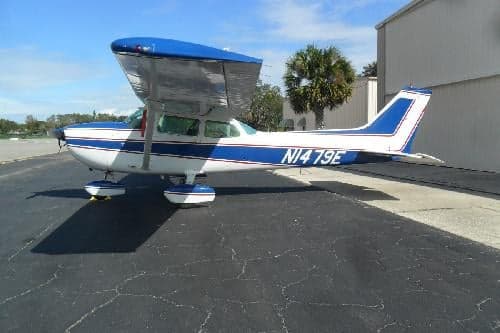 A white and blue Cessna 172 with tail number N1479E is parked on the tarmac.