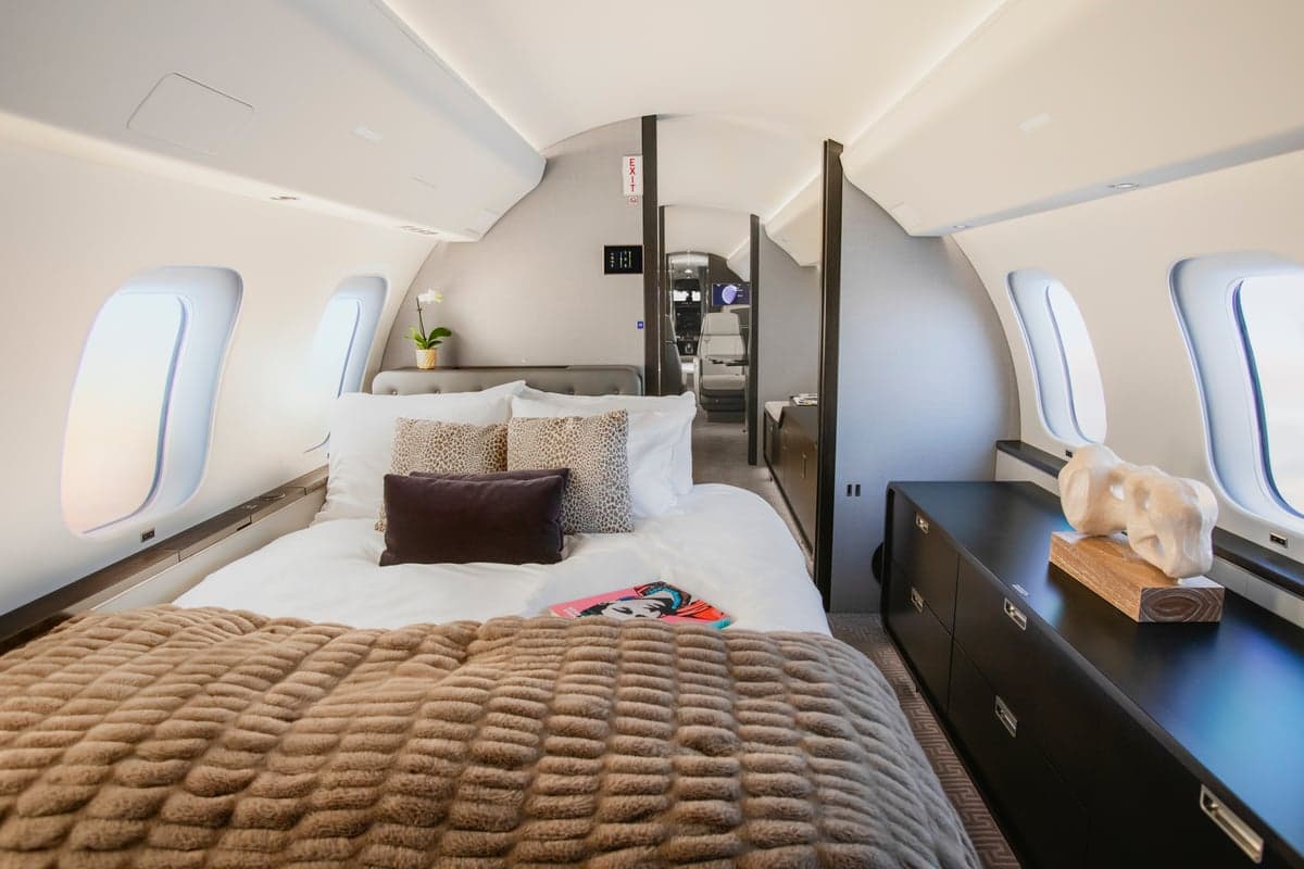 View of the aircraft interior with a bed and a dresser.