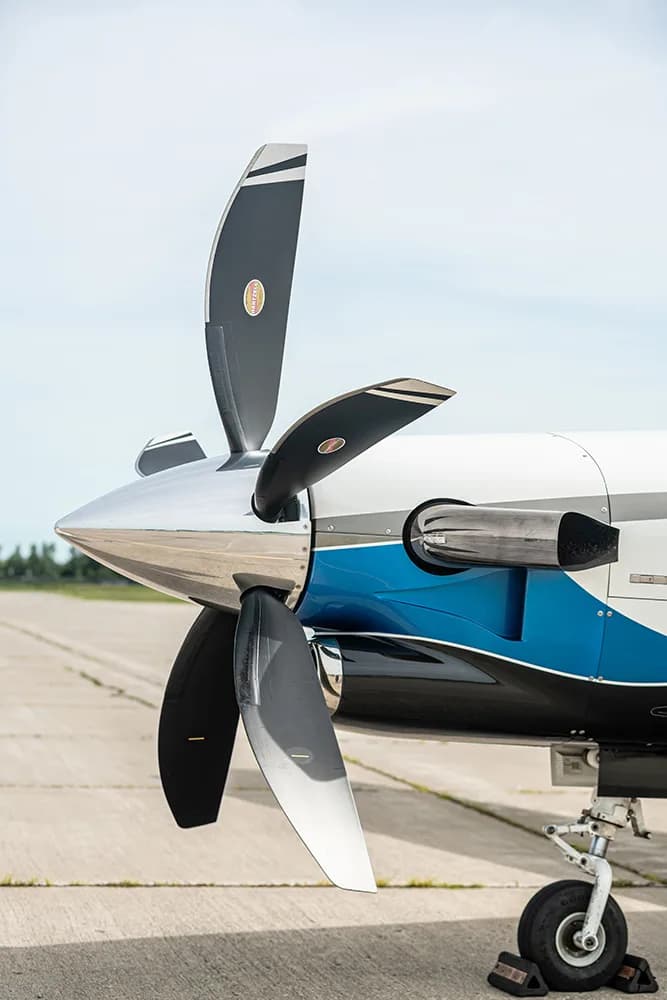 A close-up view of the five-bladed propeller and engine of a white, blue, and black TBM 960 aircraft.