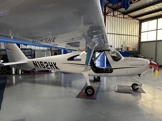 A white Cessna Skycatcher N162HK light-sport aircraft is parked in a hangar.