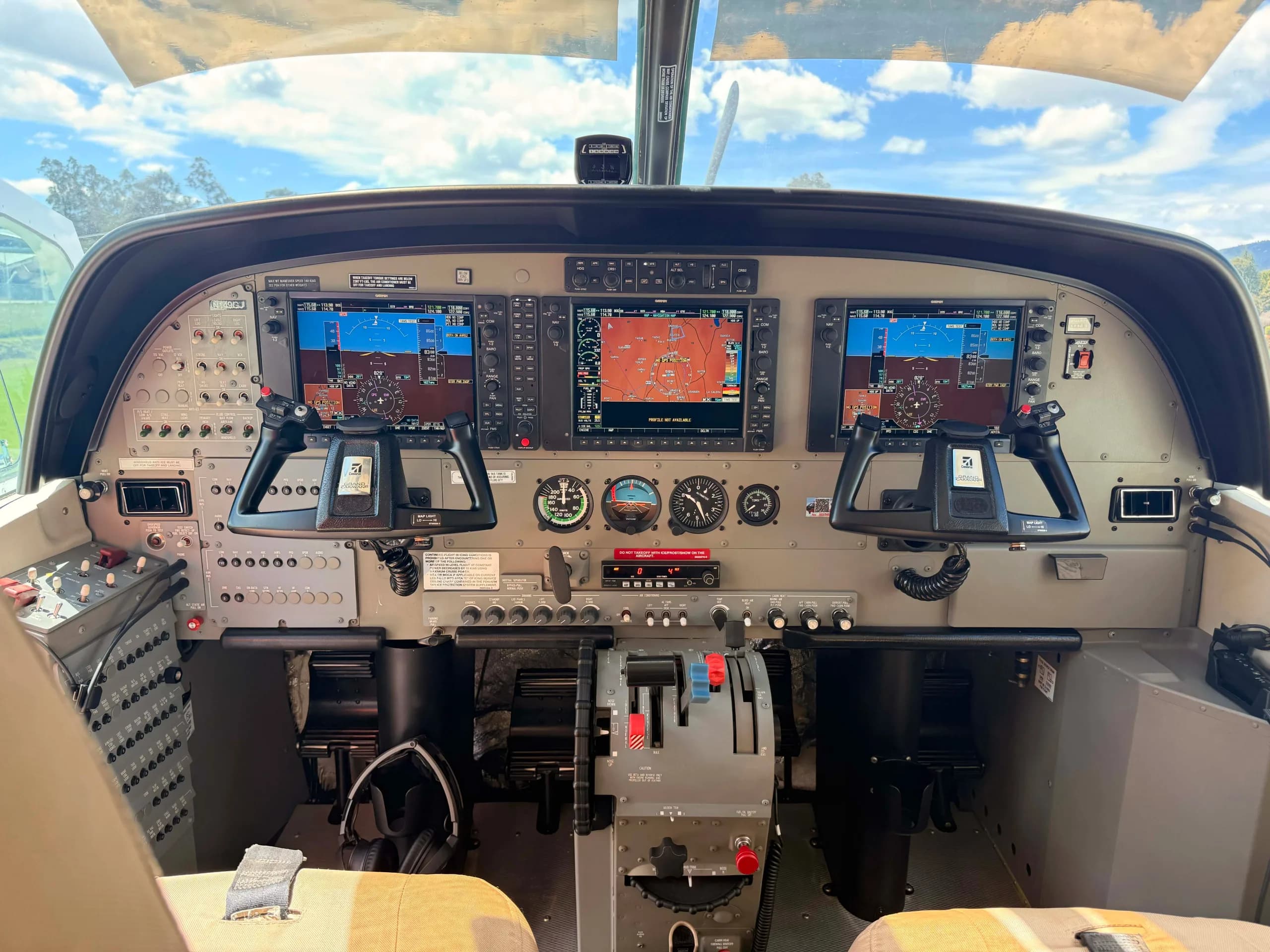 The modern glass cockpit of an aircraft with multiple display screens and controls.
